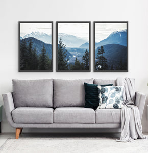 Three photo prints of blue mountains and a forest above the sofa