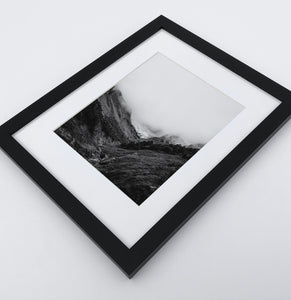A poster with a foggy mountains landscape in a black frame