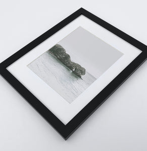 A framed photo print with a rock in the ocean