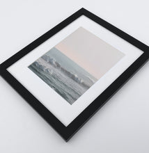 Load image into Gallery viewer, Big fluffy ocean waves in a light pink sunrise sky photo print in a black frame
