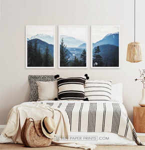Three photo prints of blue mountains and a forest above the bed