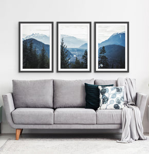 Three photo prints of blue mountains and a forest above the sofa