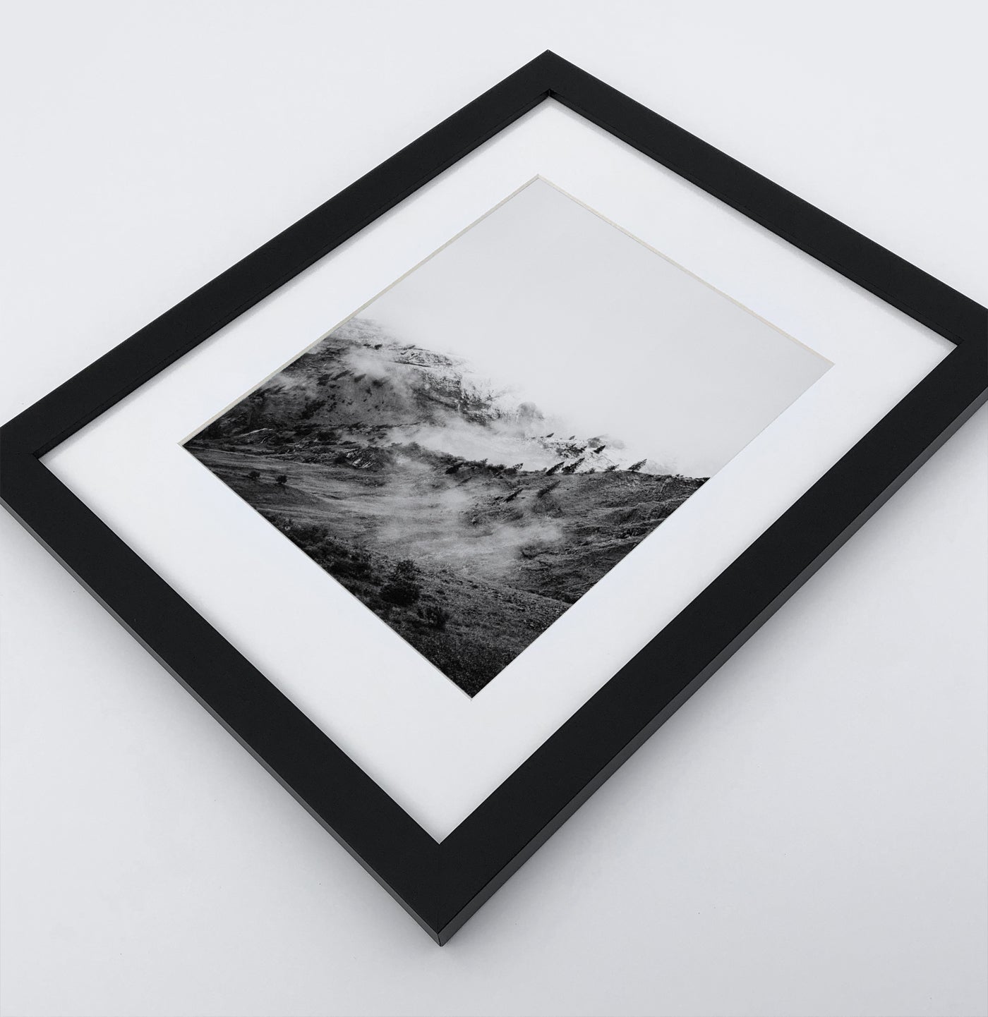 A poster with a foggy mountains landscape in a black frame