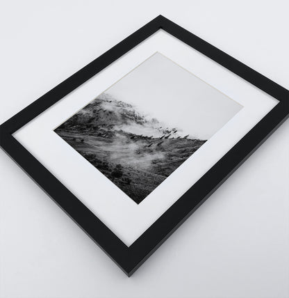 A poster with a foggy mountains landscape in a black frame