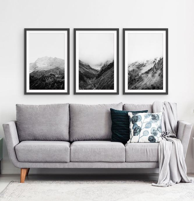 3 posters of black and white foggy mountain landscapes above a living room sofa