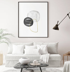 A black-framed wall art with black, silver and golden forms in a living room