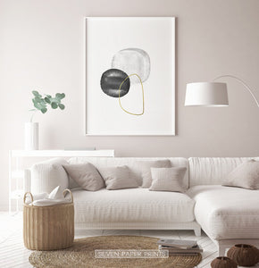 A white-framed wall art with black, silver and golden forms in a living room