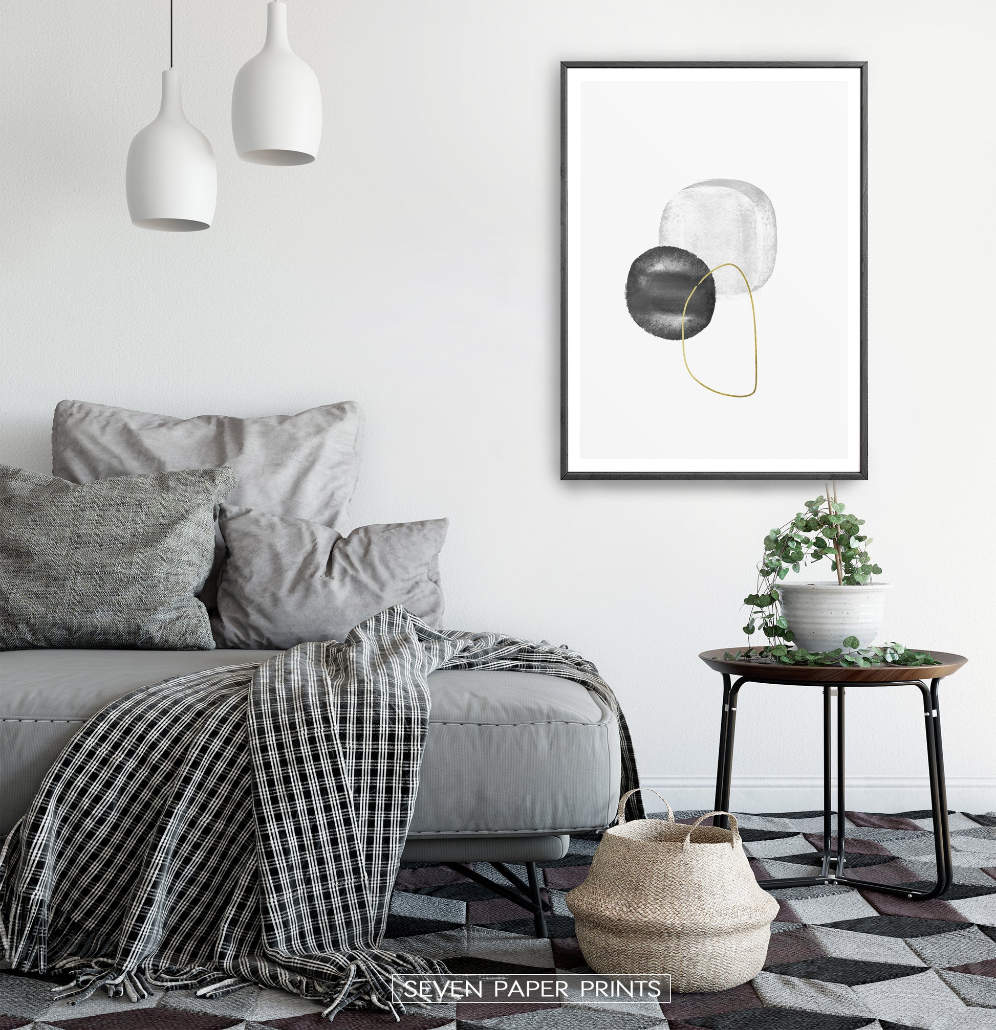 A black-framed wall art with black, silver and golden forms in a bedroom