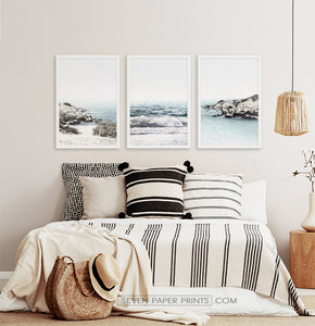 Three white shore of the ocean photos in frames above the bed