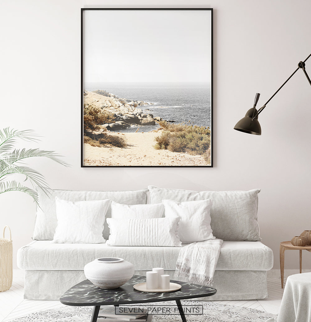 Beige gray rocky beach wall art above the white sofa in living room