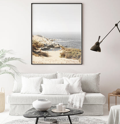 Beige gray rocky beach wall art above the white sofa in living room